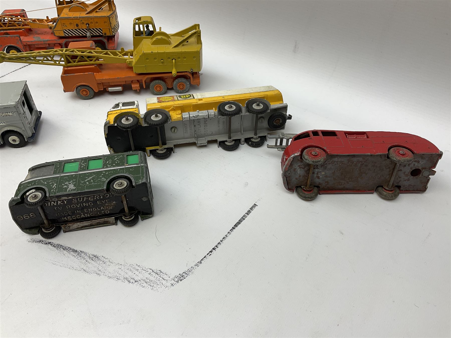 Dinky - thirteen unboxed and playworn die-cast commercial vehicles including two Supertoys 20-Ton Lorry-Mounted Cranes; Leyland Octopus Tanker; Fire Engine No.955; Extending Mast Vehicle No.969; two TV Roving Eye Vans No.968; three Ford Transit Vans; Brinks Armoured Car No.275; etc