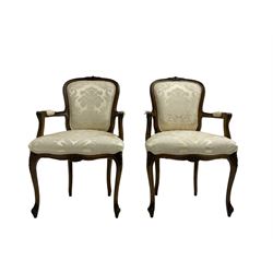 Pair Louis XVI design walnut framed salon armchairs, cresting rail with applied garland decoration, back and seat upholstered in foliate patterned ivory damask fabric, raised on cabriole supports with shell moulded knees and scrolled acanthus leaf feet 