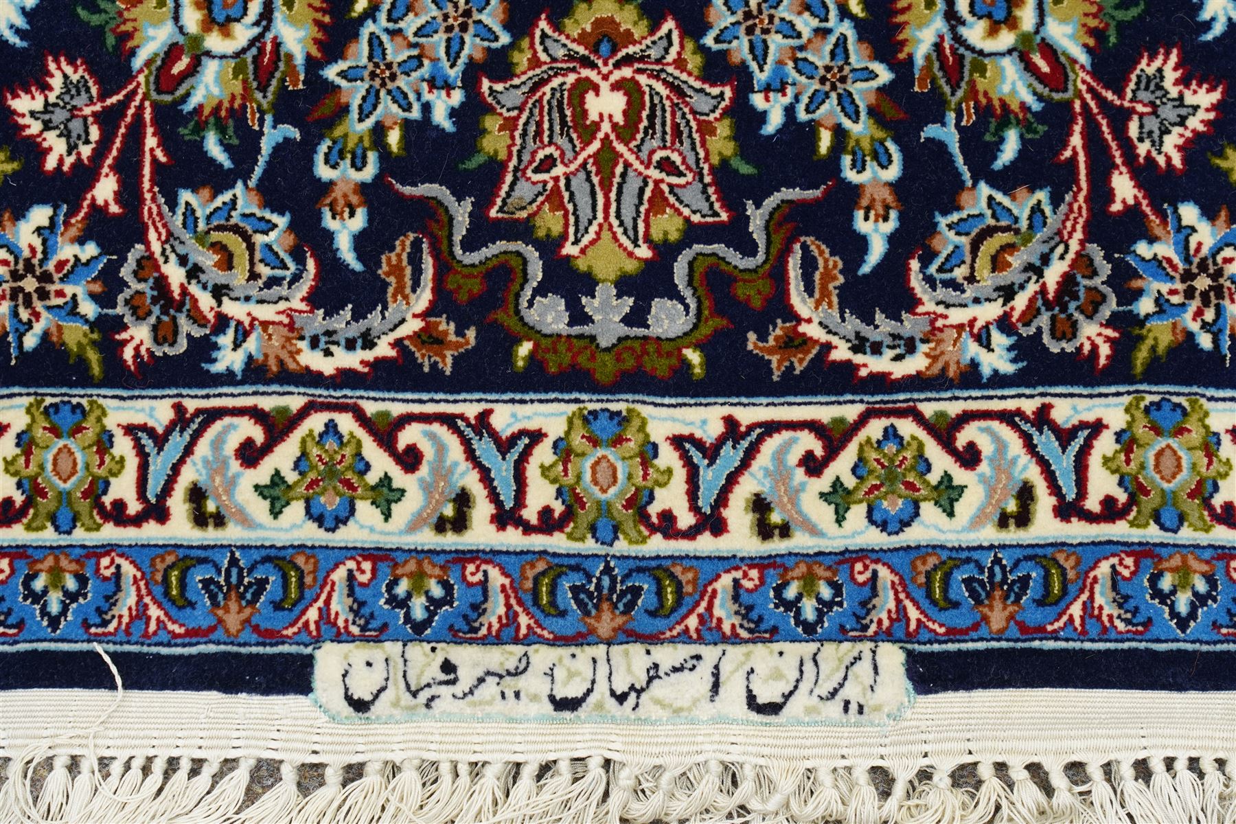 Fine Central Persian Isfahan hand-knotted rug, madder red field with central finely drawn foliate medallion issuing an intricate all-over scrolling vine design with palmettes and arabesques, enclosed by multiple conforming borders in navy ground, signed Isfahan in cartouche, silk fringe ends 