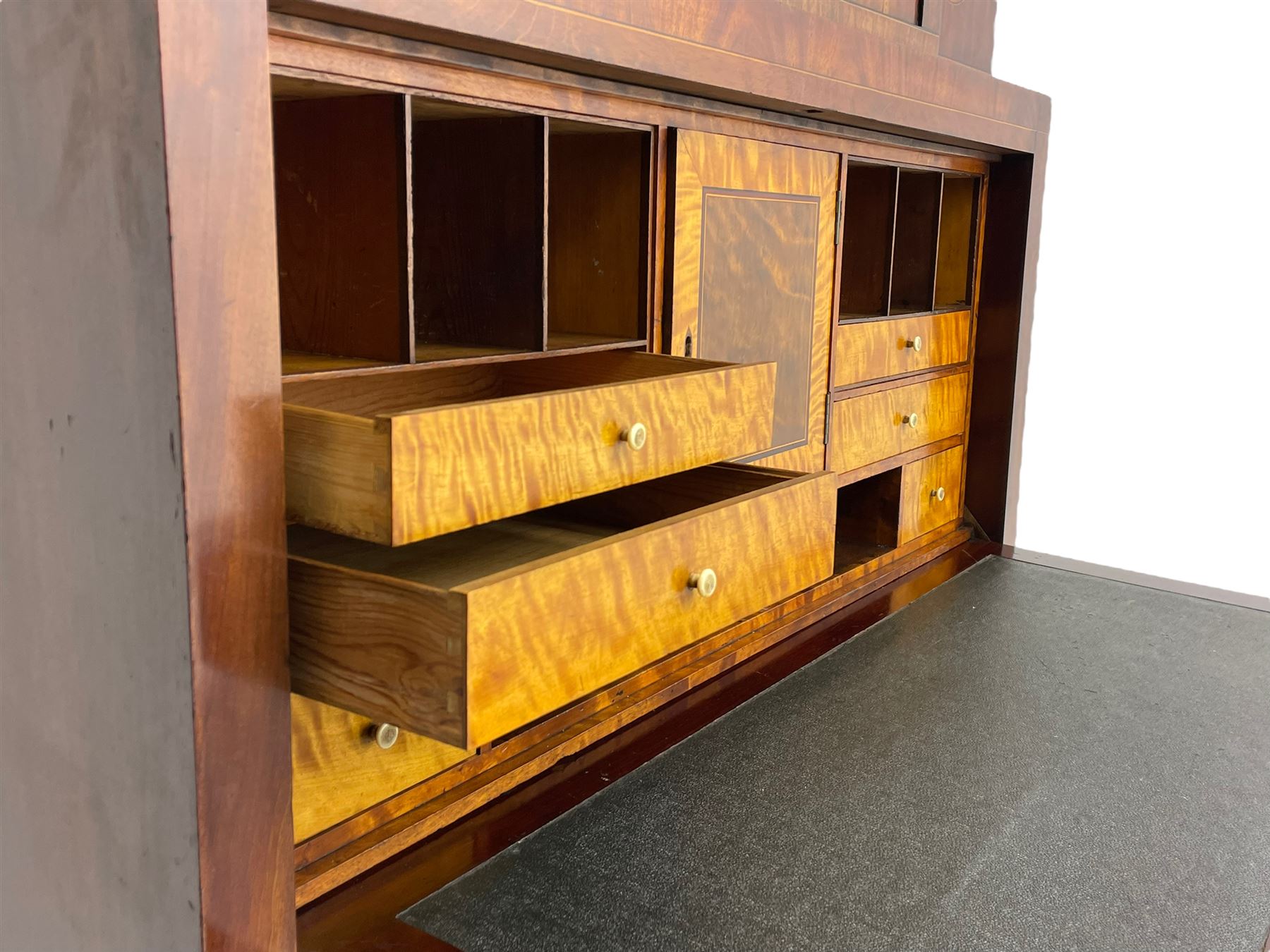Early to mid-19th century figured mahogany Continental secrétaire à abattant, stepped top fitted with single cupboard, inlaid with oval figured amboyna panels, the fall front inlaid with shell motif enclosing a satinwood interior fitted with cupboard, drawers, and pigeon holes, three long drawers below, on square tapering feet