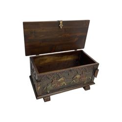 Mid-20th century carved hardwood chest, the rectangular hinged top with decorative strap hinges, the front and sides deeply carved with medieval-style jousting knights, heraldic shields, and architectural elements, raised on shaped block feet