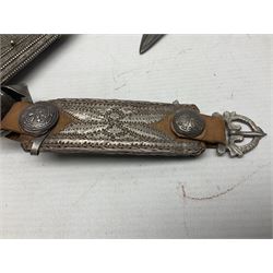 Omani Khanjar dagger, the 19cm curved blade with pronounced medial rib to either side, waisted hilt with dome shaped pommel and silver covered horn grip decorated with filigree bands, floral motifs and beadwork; in an intricately filigree decorated silver and leather scabbard with silver rings woven into the belt mount and fitted with original silver thread-work belt L34cm overall belt length 94cm