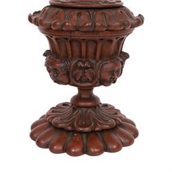 Carved wooden urn. decorated in relief with carved faces within foliage, with a Satyr finial, H25cm 