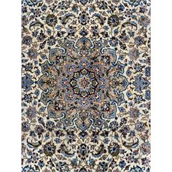 Central Persian Najafabad hand-knotted carpet, the ivory field with a central floral medallion radiating palmettes and arabesques in tones of blue, lilac and tan, enclosed by a wide navy border of scrolling vine and rosette motifs, with red spandrels and multiple guard stripes