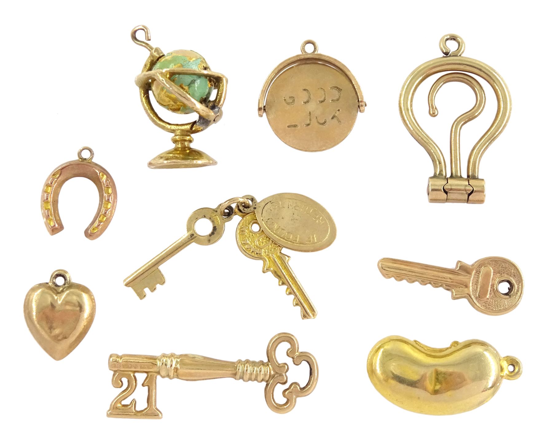 Nine 9ct gold pendant / charms including enamel globe by Georg Jensen, 21 key, bean, 'Good Luck', keys, heart and horseshoe