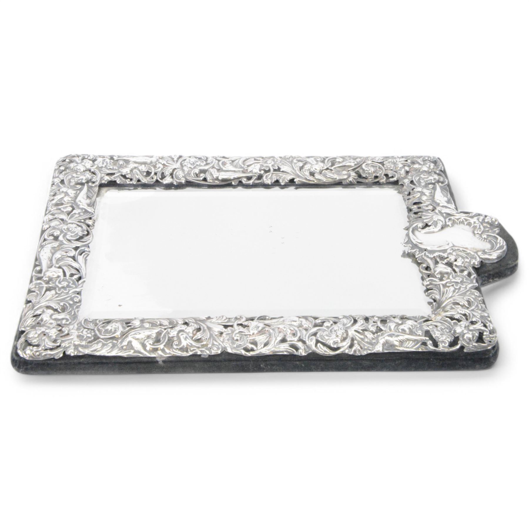 Edwardian silver mounted dressing table mirror, the bevelled mirror plate with silver surround embossed with flowers, C scrolls, putti and birds, with velvet easel support verso, hallmarked London 1903, maker's mark WC, probably for William Comyns & Sons, H33cm