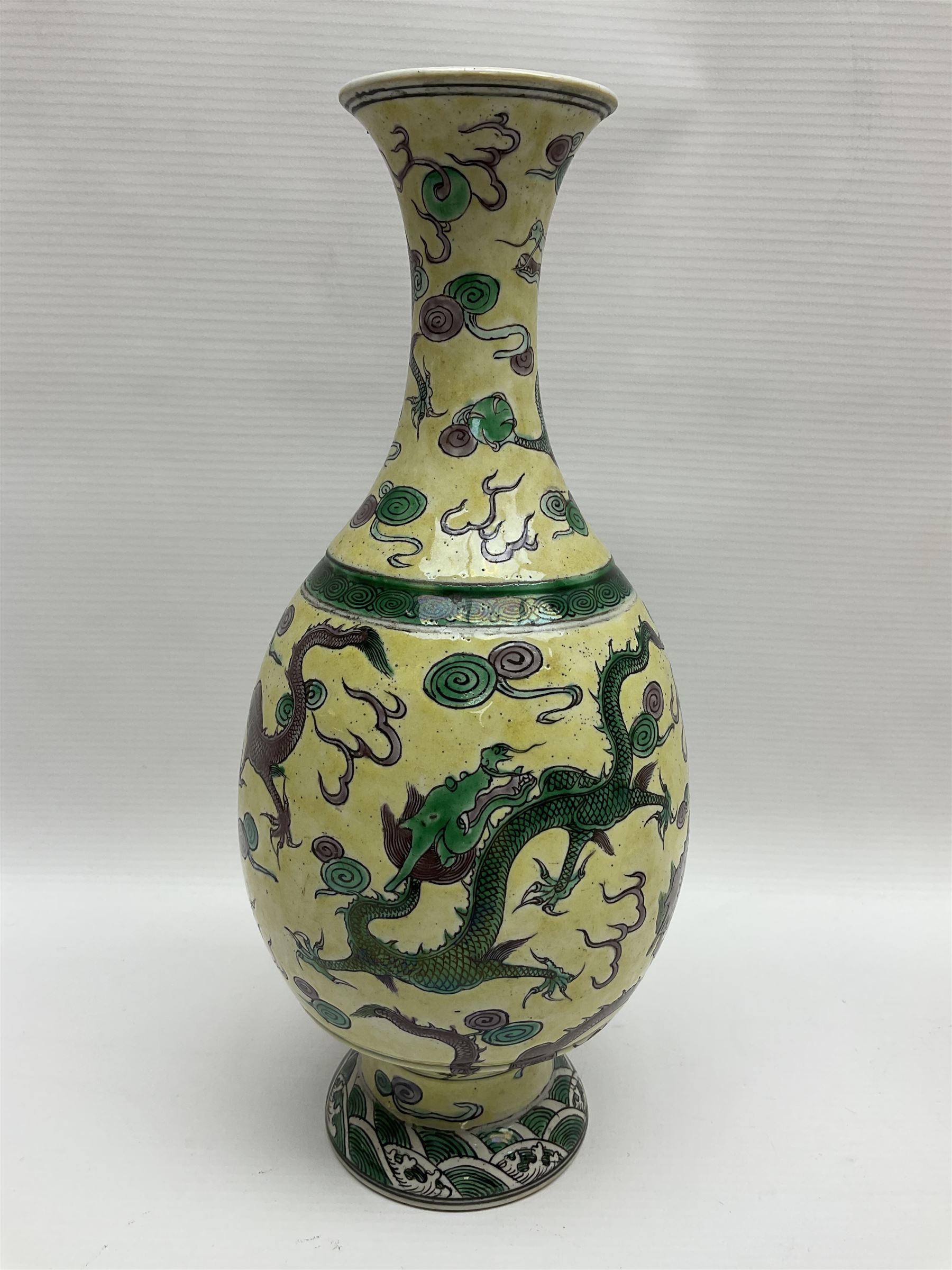 20th century Chinese Famille Verte vase, of slender ovoid form with tapering neck and flared rim, decorated with green and grey enamel with dragons chasing flaming pearls amongst auspicious clouds upon a yellow ground, H30cm