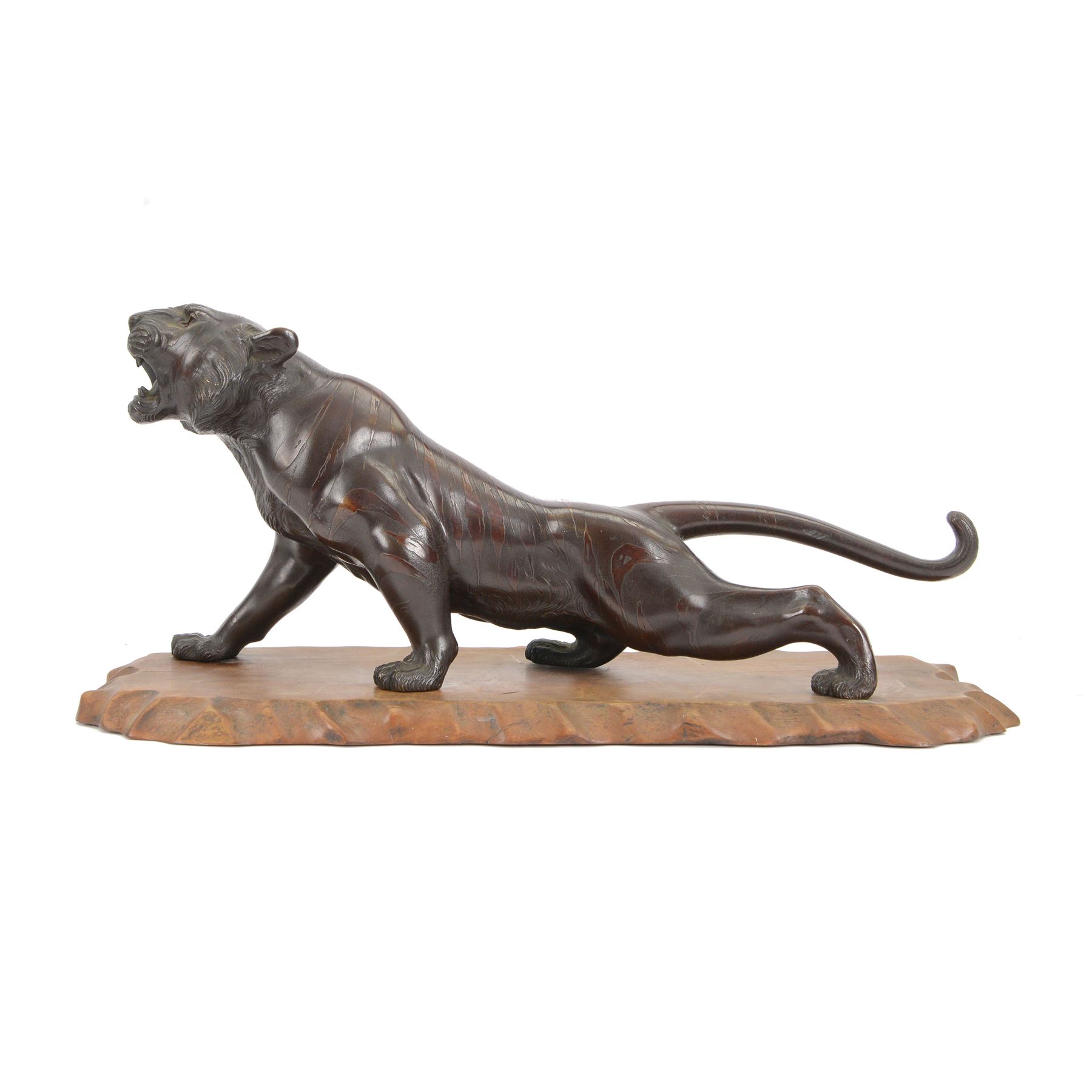Japanese Meiji period bronze, modelled as a crouching tiger, its head raised in a roar, with glossy stripes and naturalistic mane, with seal mark for Mitsumoto saku, upon a carved softwood stand, bronze H20.5cm L46cm
