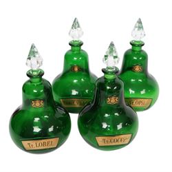 Set of four 20th century Royal Pharmaceutical Society green glass bottles, of bellied form with clear cut glass spire stopper, each body bearing gilt label in Latin: Tr.OPii., Tr.COCCi., Tr.CANNAB., and Tr.LOBEL., and gilt Royal Pharmaceutical Society crest to neck, H25cm

Provenance: From the collection of the family of Peter Green, a practising pharmacist whose career spanned the mid to late 20th century. During his professional life he managed pharmacies in Yeovil, Somerset, and later Selles Chemist in Filey, North Yorkshire, before purchasing and running his own business, Peter Green Pharmacy, located in the Market Place, Malton. The bottles were displayed as part of the traditional shop fittings in both the Filey and Malton pharmacies and were retained as part of his collection.