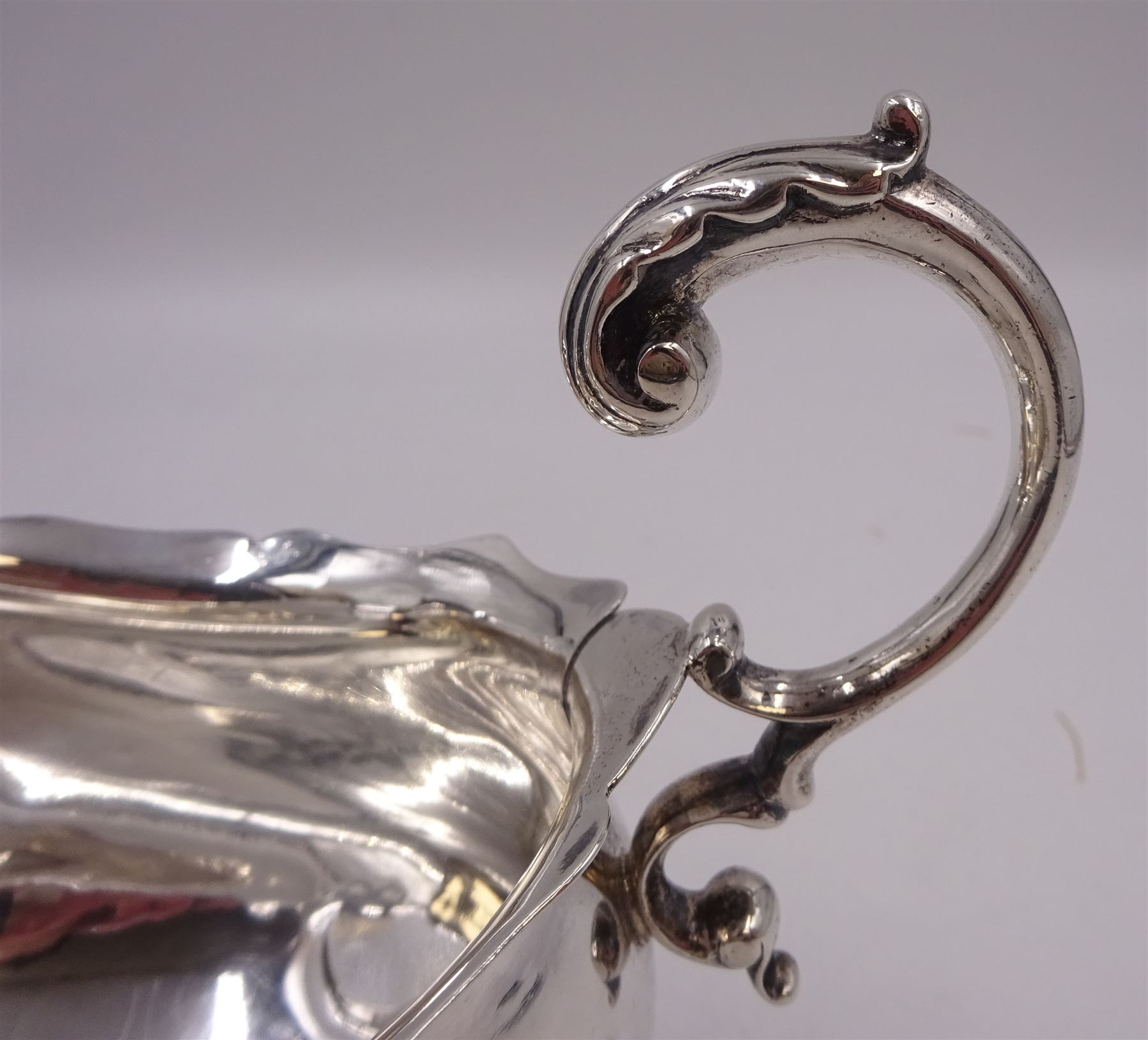 Victorian silver sauce boat, of typical plain form, with shaped rim and acanthus capped flying scroll handle, upon three hoof feet, hallmarked Walker and Hall, Sheffield 1899, including handle H12cm