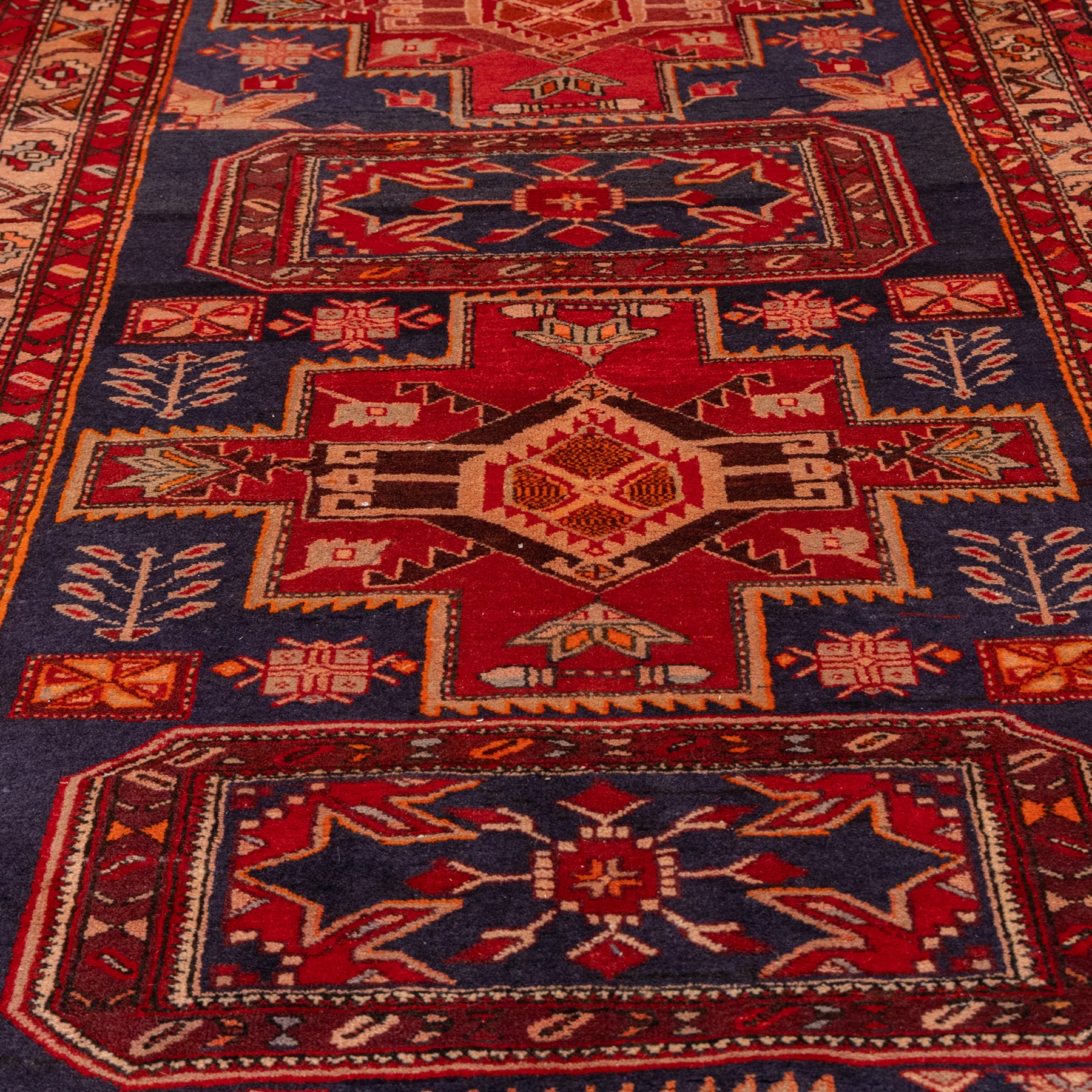 North West Persian runner, the indigo field decorated with three stepped cruciform medallions alternating with two octagonal panels, interspersed with stylised flowerheads and foliage, enclosed by an ivory ground floral border and red guard bands