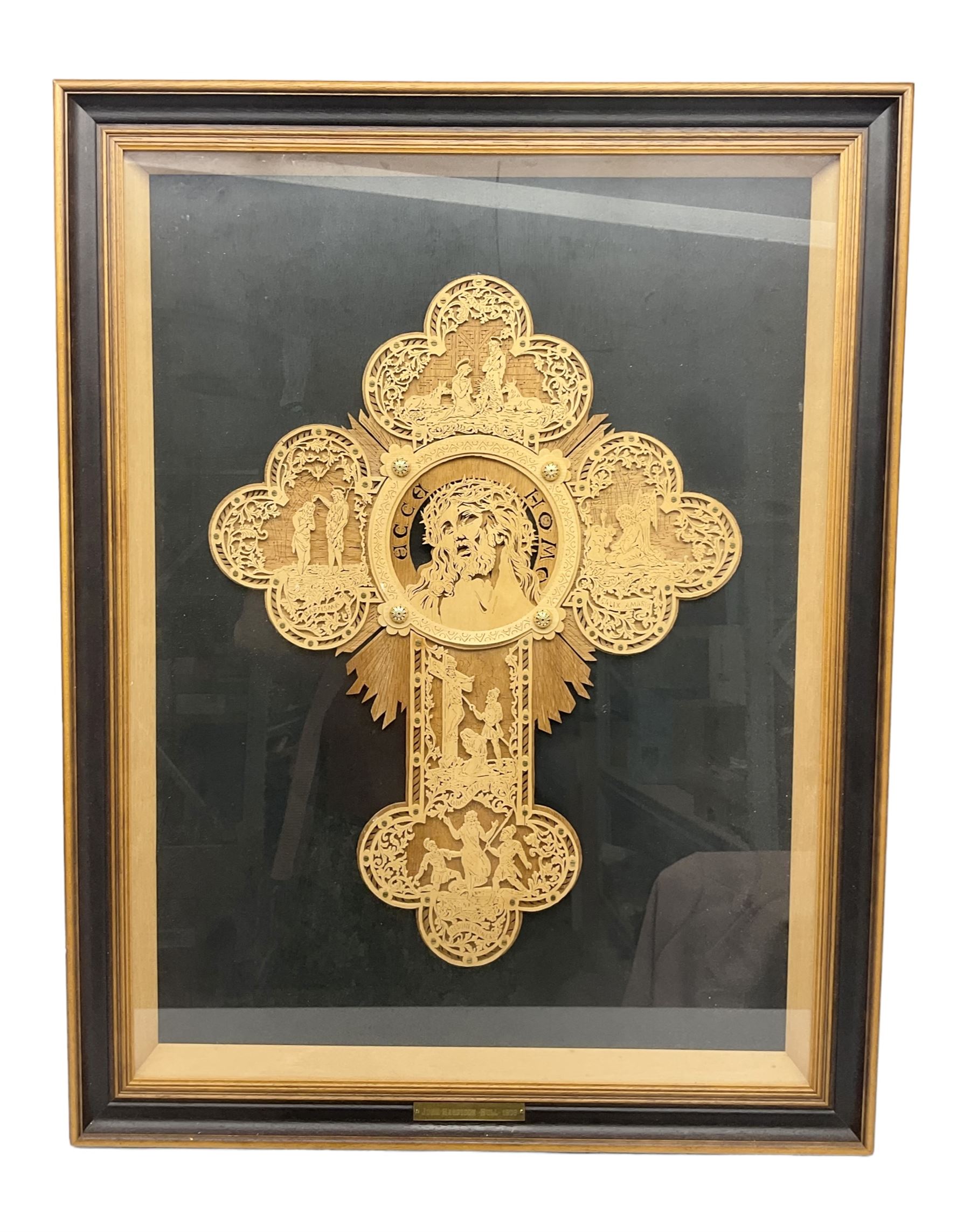 Cork carving of a religious cross depicting intricate scenes of various religious figures and motifs amongst trees and foliage, with central circular panel of Jesus Christ, in glazed frame, H95cm