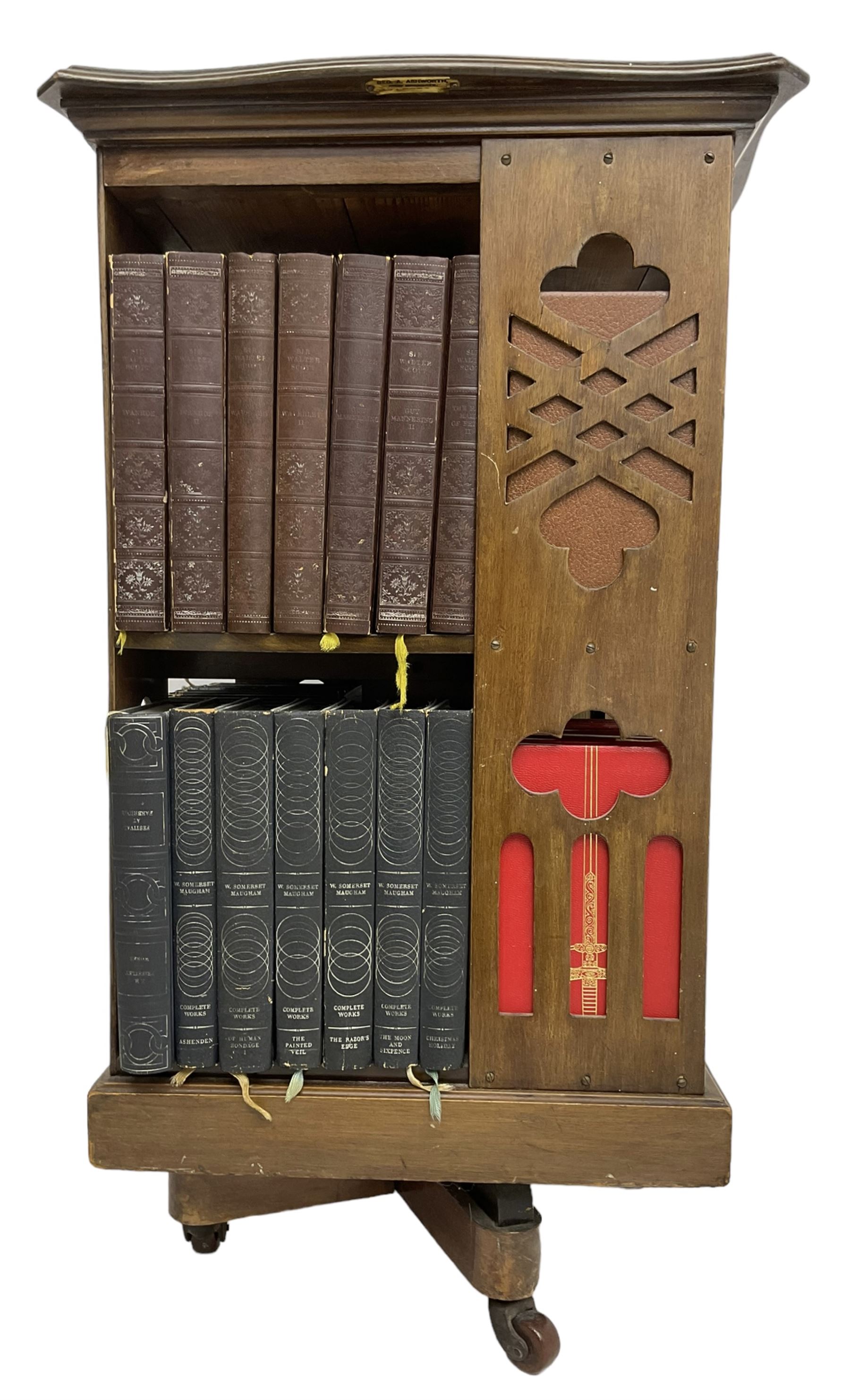 Late Victorian revolving bookcase, shaped square top over fretwork supports of geometric and arcade design, on a swivel action base with ceramic castors