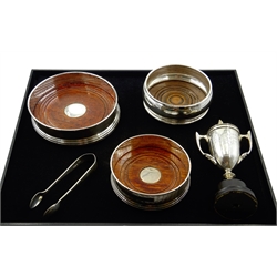  Three silver wine coasters with turned wooden base by W I Broadway & Co and WEV, pair of silver sugar tongs and small silver trophy, all hallmarked (5)  