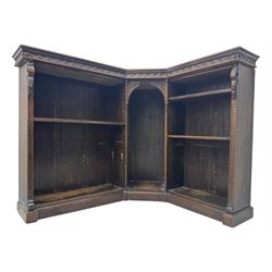 Victorian carved oak corner bookcase, L-shaped form, moulded top over lunette carved frieze, decorated with S-scroll and mask carved corbels with trailing acanthus leaves, fitted with adjustable shelves, on moulded plinth base 