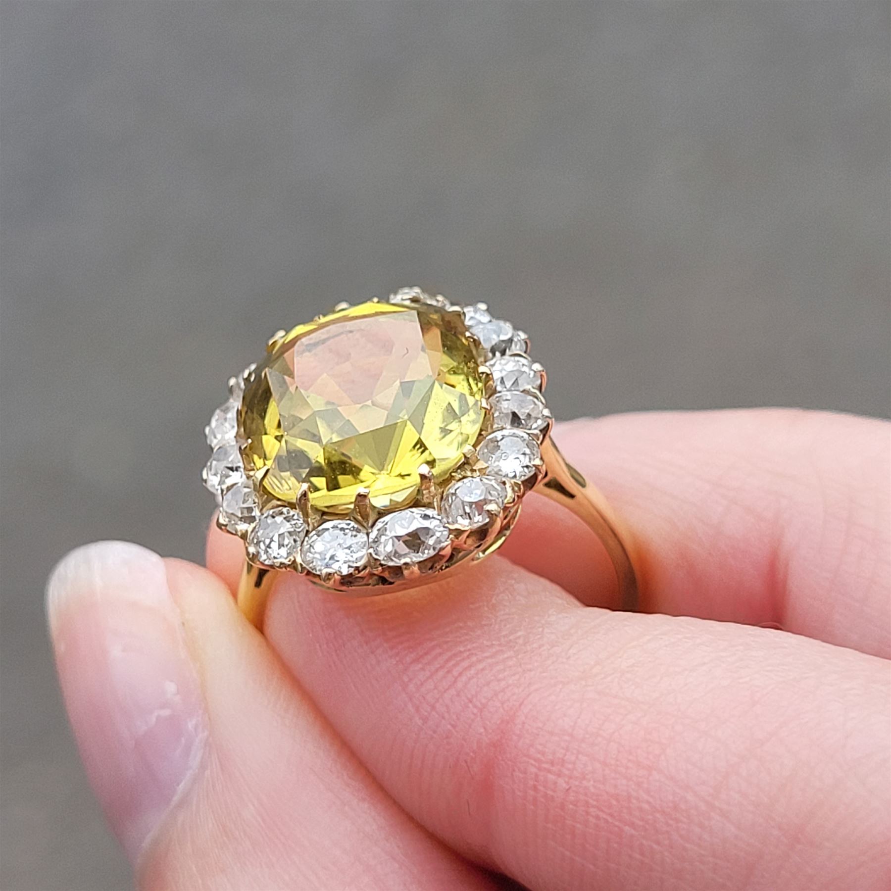 Early 20th century gold chrysoberyl and diamond cluster ring, single cushion cut yellow / green chrysoberyl of approx 8.00 carat, surrounded by sixteen old cut diamonds, stamped 18ct, total diamond weight approx 1.10 carat