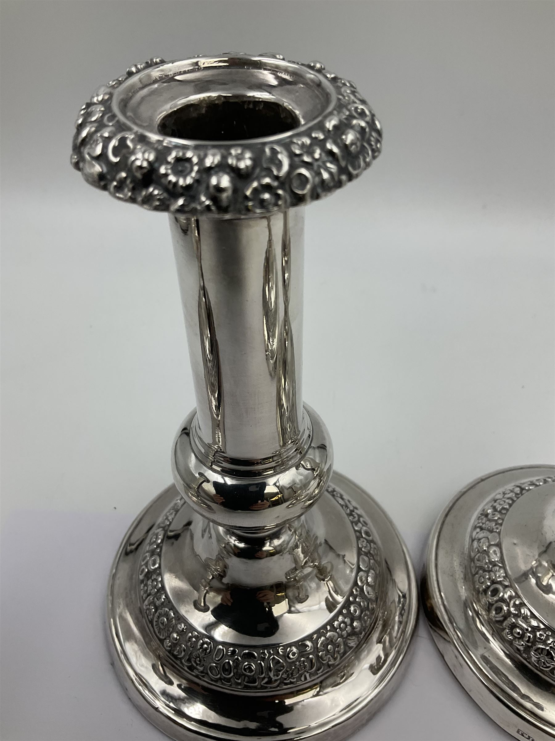 Four George III silver candlesticks, each upon knopped stem and weighted circular stepped foot, the foot and removable sconce repousse decorated with a band of flower heads, hallmarked to sconce and foot Thomas & John Settle, Sheffield 1820, H17.5cm