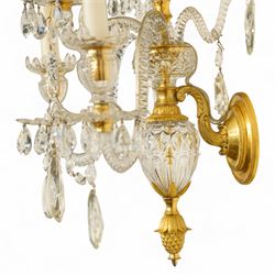 Pair of George III ormolu and cut-glass wall-lights, each with a tall central urn-shaped finial above a series of faceted glass spires and scrolled branches, the ormolu-mounted nozzles and drip pans hung with festoons of cut-glass drops and pear-shaped pendants, the lower section centred by a pineapple finial, wired for electricity