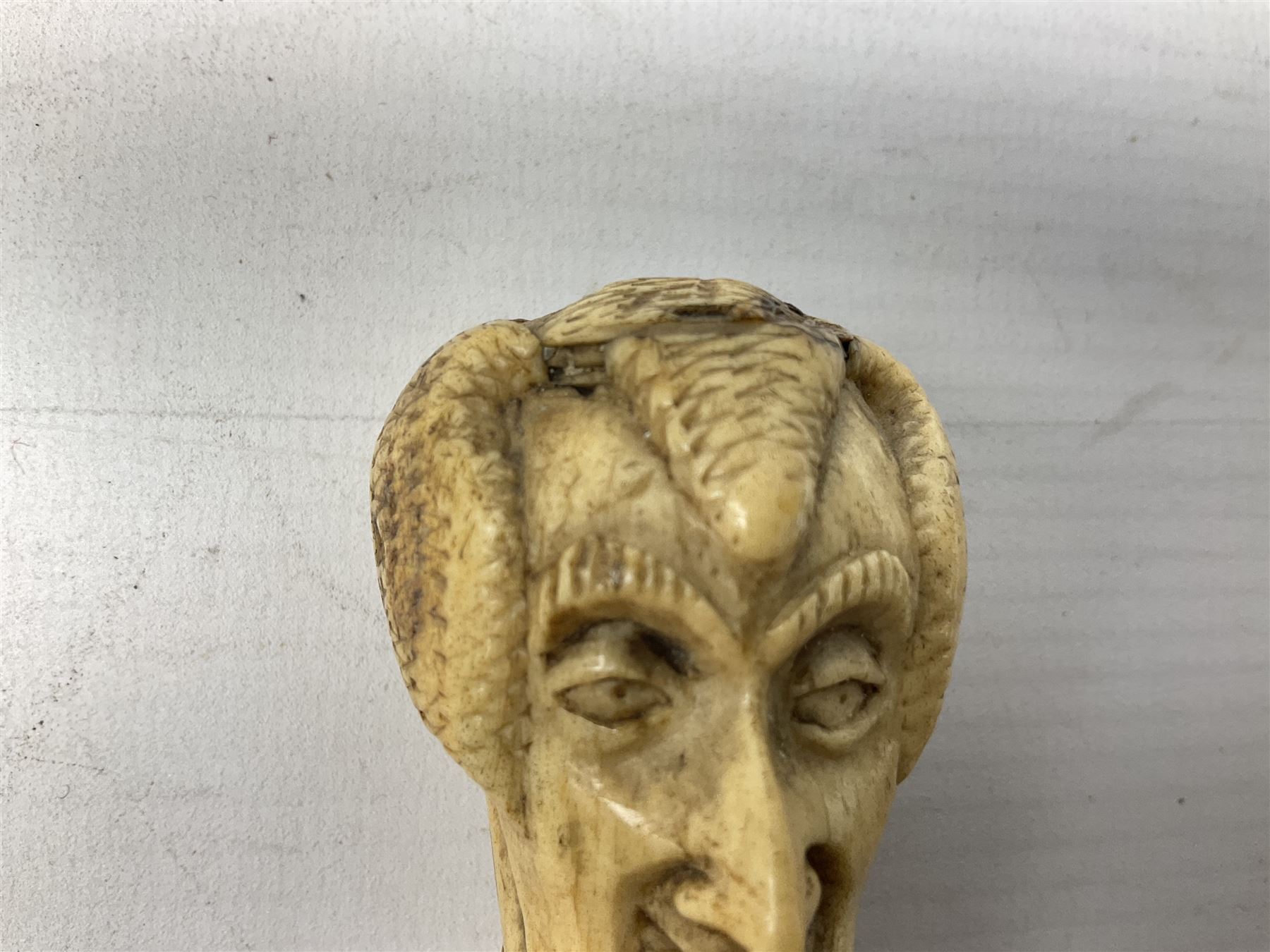 19th century carved ivory walking cane handle, modelled as the head of a greyhound with inset glass eyes, together with a further 19th century ivory example, modelled as a caricature of a gentleman's head, (2)