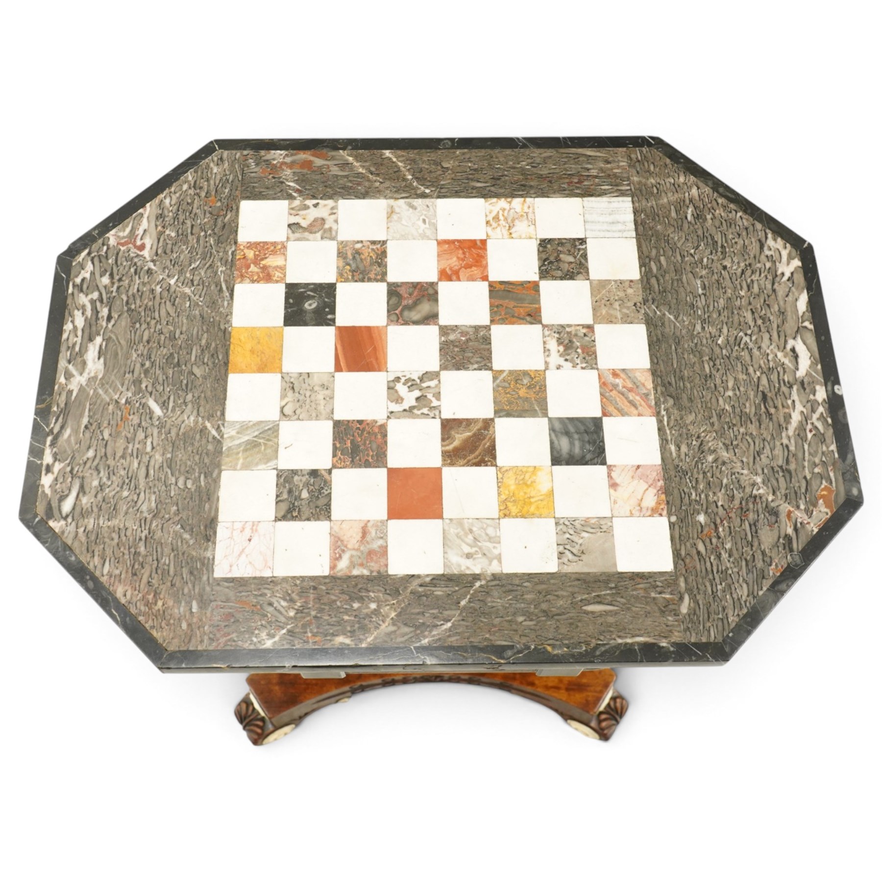 Early 19th century Anglo-Indian rosewood and specimen marble chess table, the octagonal top inset with a chequerboard of various coloured marbles within a broad fossil marble border and black marble edge, over a foliate and rosette carved frieze and turned-and-tapering pedestal with lotus-carved decoration, on a concave-sided quadripartite platform base with anthemion carved scroll terminals, inset ivory roundels and brass bun feet