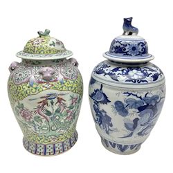 Chinese jar and cover, decorated in polychrome enamels with a panel depicting birds amongst peonies, surrounded by floral and foliate decoration on a yellow ground, with four pink mask handles and dog finial to cover, with retail sticker beneath for Wing Tung Hing, together with a similar blue and white example, decorated with figural scenes amongst trees and flowers, the cover with a temple dog finial, with printed mark beneath, tallest H41cm