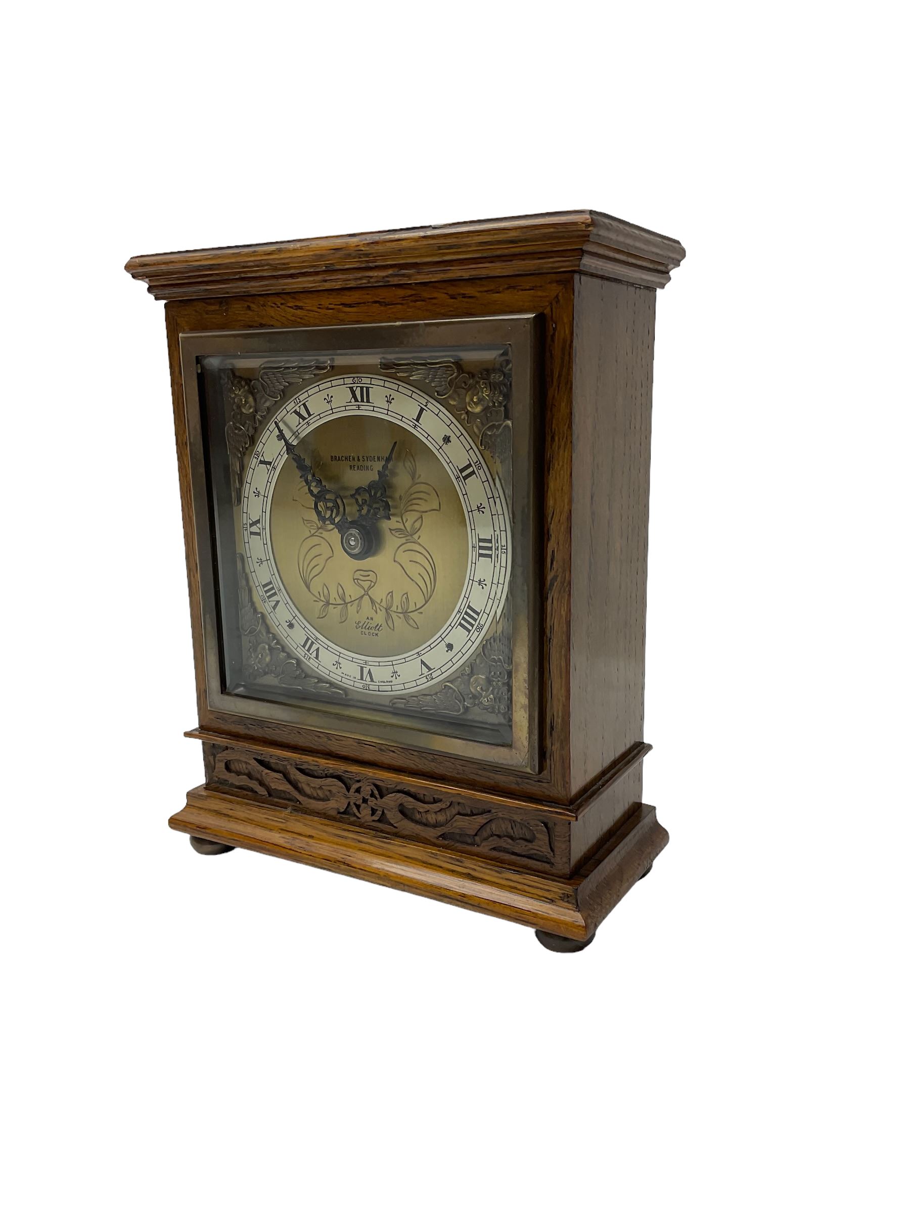Elliot - oak cased 1950’s 8-day timepiece mantle clock, with a balance wheel movement wound and set from the rear, flat topped case with a carved panel raised on bun feet, square brass dial, silver chapter ring, spandrels and  decoratively engraved dial centre inscribed “Bracher & Sydenham, Reading”