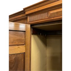 Edwardian walnut combination breakfront triple wardrobe, projecting cornice over cushioned and fluted frieze, central fielded panelled cupboard carved with foliate decoration above two short and three long drawers, flanked by two bevelled mirror doors enclosing hanging hooks with single drawers to base, retailed by J Tonks & Sons, Scarborough