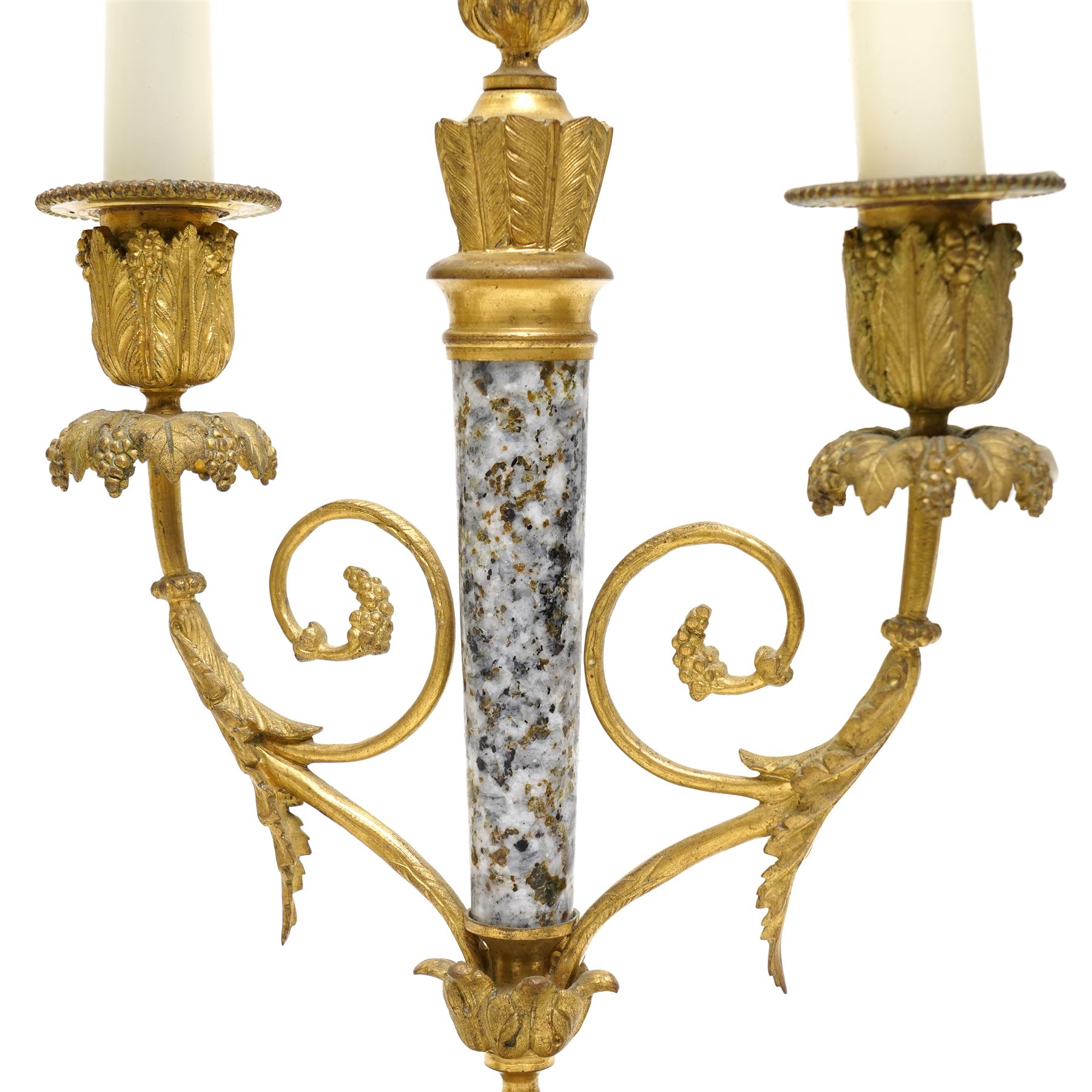 French- early 20th century portico clock garniture, 8-day drum movement decorated with laurel leaves to the glazed bezel and surmounted by a decorative urn with scroll handles, raised by four matching columns on a granite effect oval base with toupee feet, convex enamel dial with gilt pierced hands, Arabic numerals, minute markers and a garland of flowers, twin train Parisian rack striking movement, striking the hours and half hours on a bell. With a sunburst pendulum and key and a matching pair of two-light candelabra.