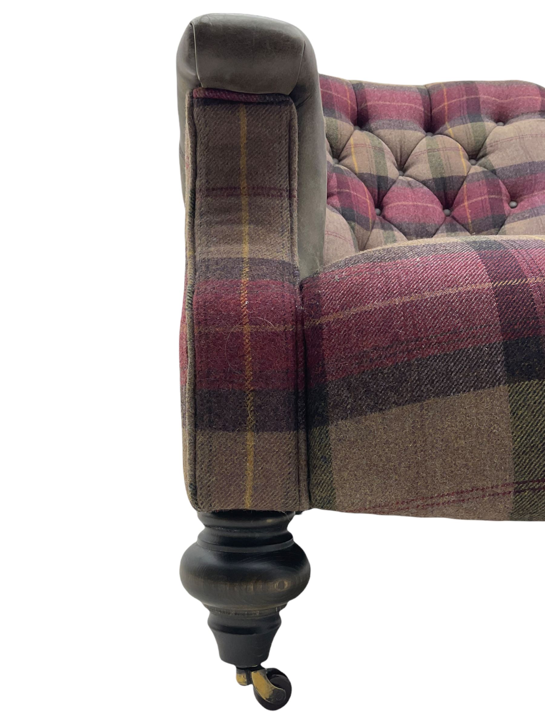 John Sankey - low armchair, buttoned back upholstered in tartan patterned fabric with contrasting grey leather, raised on turned and ebonised front feet with brass and ceramic castors, with matching foot stool