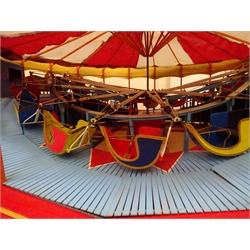  Large brightly painted electrically operated scratch built wooden and metal fairground roundabout with eighteen sleigh shaped cars revolving above an undulating boardwalk beneath a red and white cloth covered canopy with sets of steps to either side D103cm excluding steps H46cm  