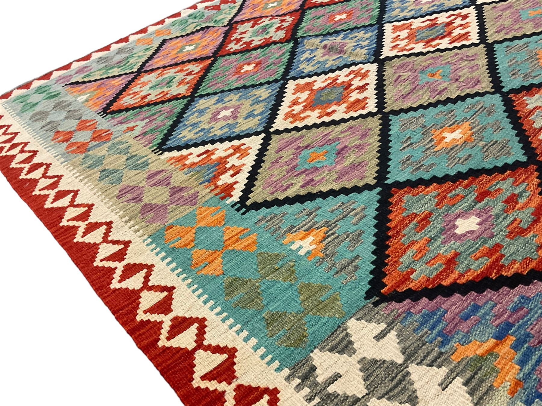Anatolian Turkish Kilim multi-colour rug, decorated with all over lozenges in contrasting colours with dark indigo outline, the multi-band ivory and red border with repeating geometric shapes and small lozenges or diamonds