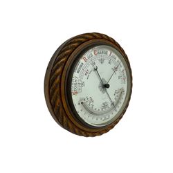 1930’s aneroid barometer with a 10” porcelain dial recording barometric air pressure from 28 to 31 inches with weather predictions, curved mercury thermometer, steel indicating hand and brass recording hand, oak case with carved rope work decoration.