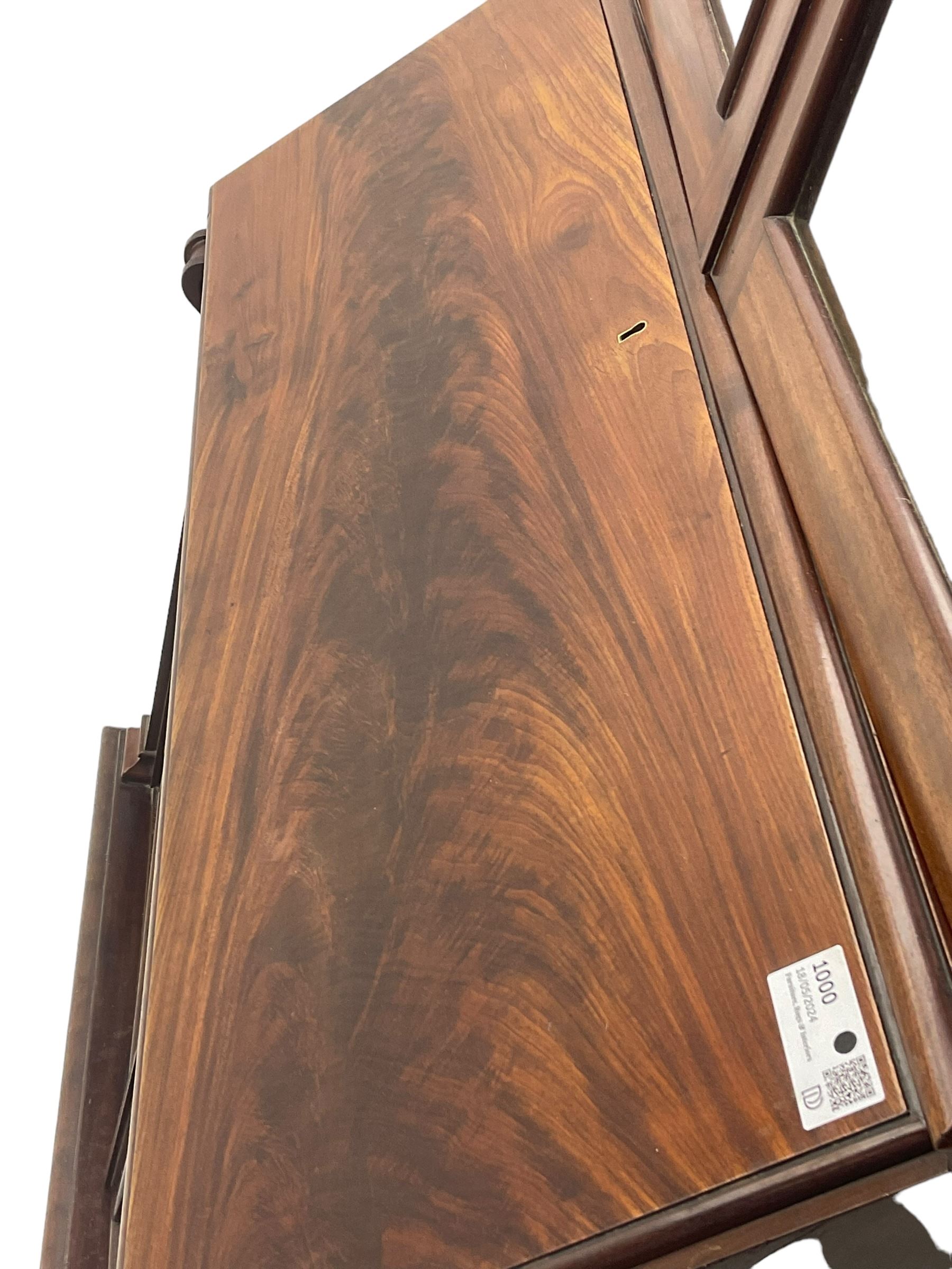 Early 19th century figured mahogany bureau bookcase, projecting splay moulded cornice over three adjustable shelves enclosed by two glazed doors, fall front revealing pigeonholes, cupboard and drawers, pull-out strays with scroll carved terminals, double cupboard with two panelled doors, on turned feet 