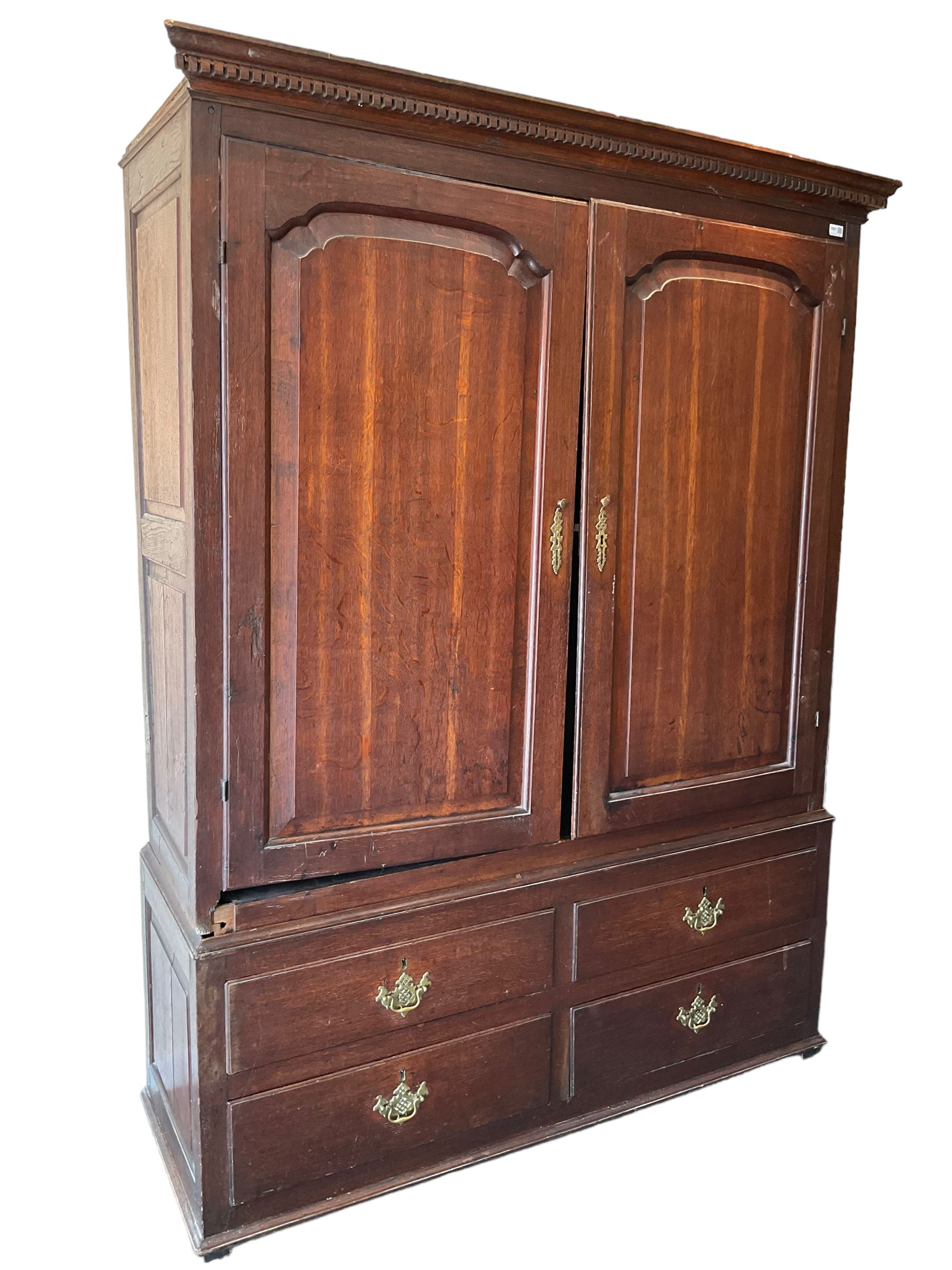 George III oak press cupboard, dentil cornice over two arch fielded panel doors, the base fitted with four drawers with pressed brass handle plates