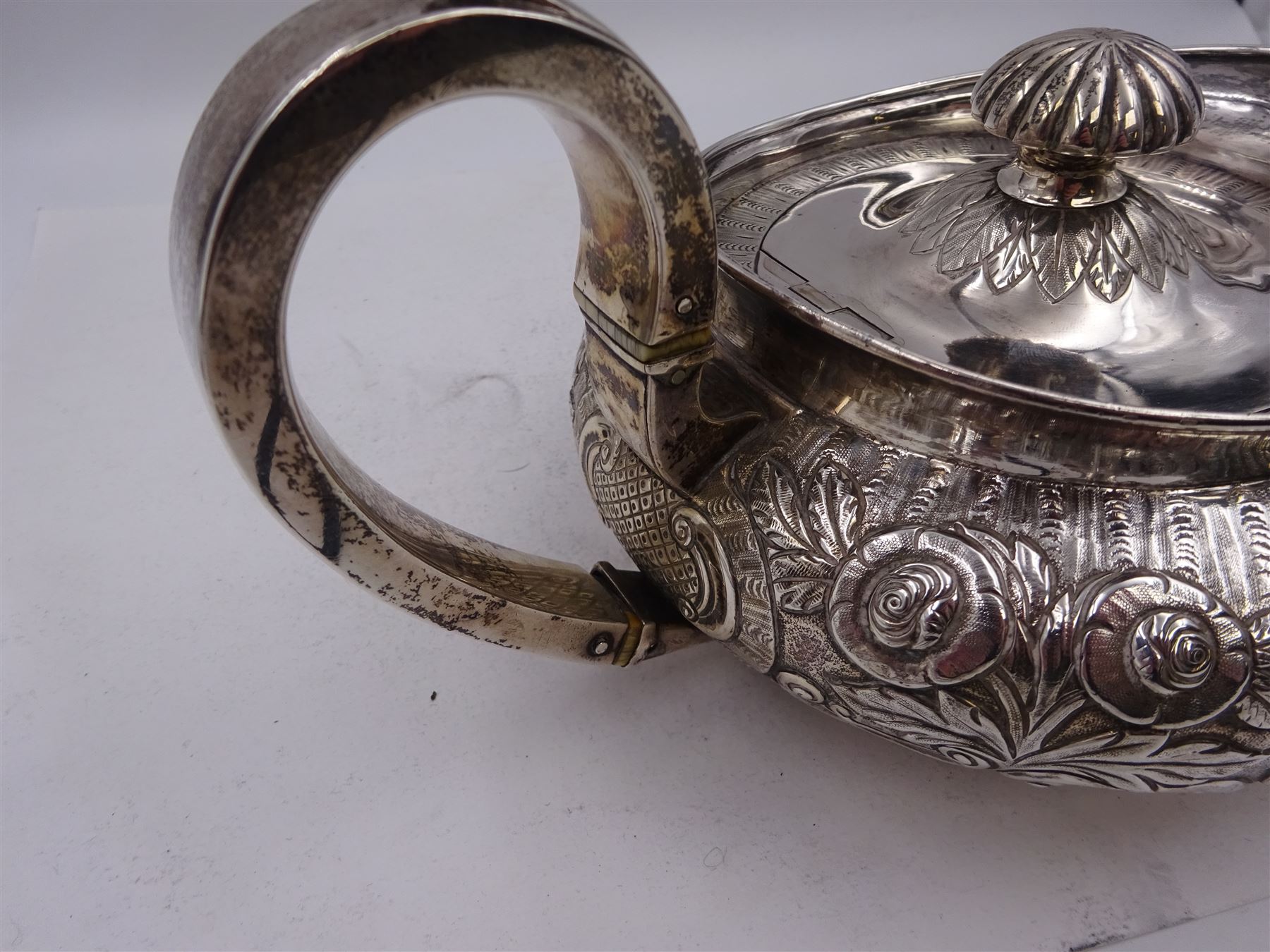 George III Irish silver teapot, of squat circular form, the body with repousse and chased floral and C scroll decoration, with capped C handle and ivory insulators, engraved to base 'Presented to Troop Sergeant Major John Percival, of the 4th Dragoon Guards by Alex D. Tait, Esq, late Captain in that corps as a mark of approbation of his steady and upright conduct when Sergeant Major of his Troop, Dublin, June 2nd 1843', hallmarked William Law, Dublin 1817, H12.5cm, This item has been registered for sale under Section 10 of the APHA Ivory Act