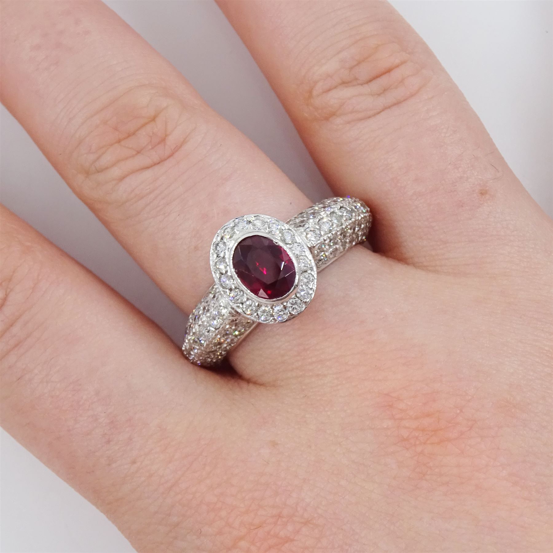 18ct white gold oval cut ruby and round brilliant cut diamond cluster ring, with pave set diamond shoulders, stamped 750, ruby approx 1.05 carat, total diamond weight approx 1.00 carat