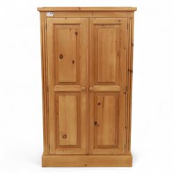 Modern stripped pine two-door wardrobe, the fielded panel doors with turned knob handles, opening to a double rail hanging interior, beneath a stepped cornice and raised on plinth base