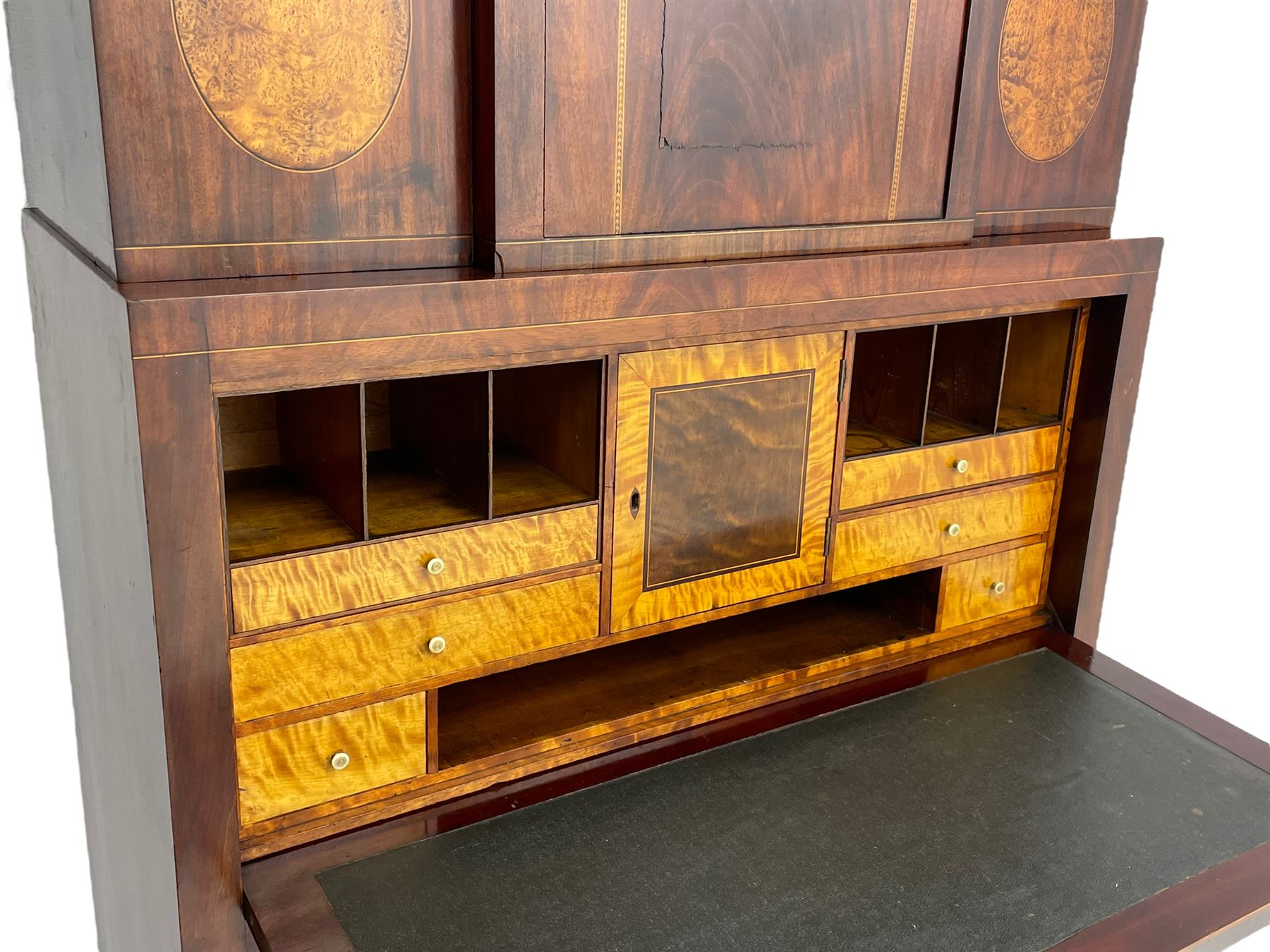 Early to mid-19th century figured mahogany Continental secrétaire à abattant, stepped top fitted with single cupboard, inlaid with oval figured amboyna panels, the fall front inlaid with shell motif enclosing a satinwood interior fitted with cupboard, drawers, and pigeon holes, three long drawers below, on square tapering feet