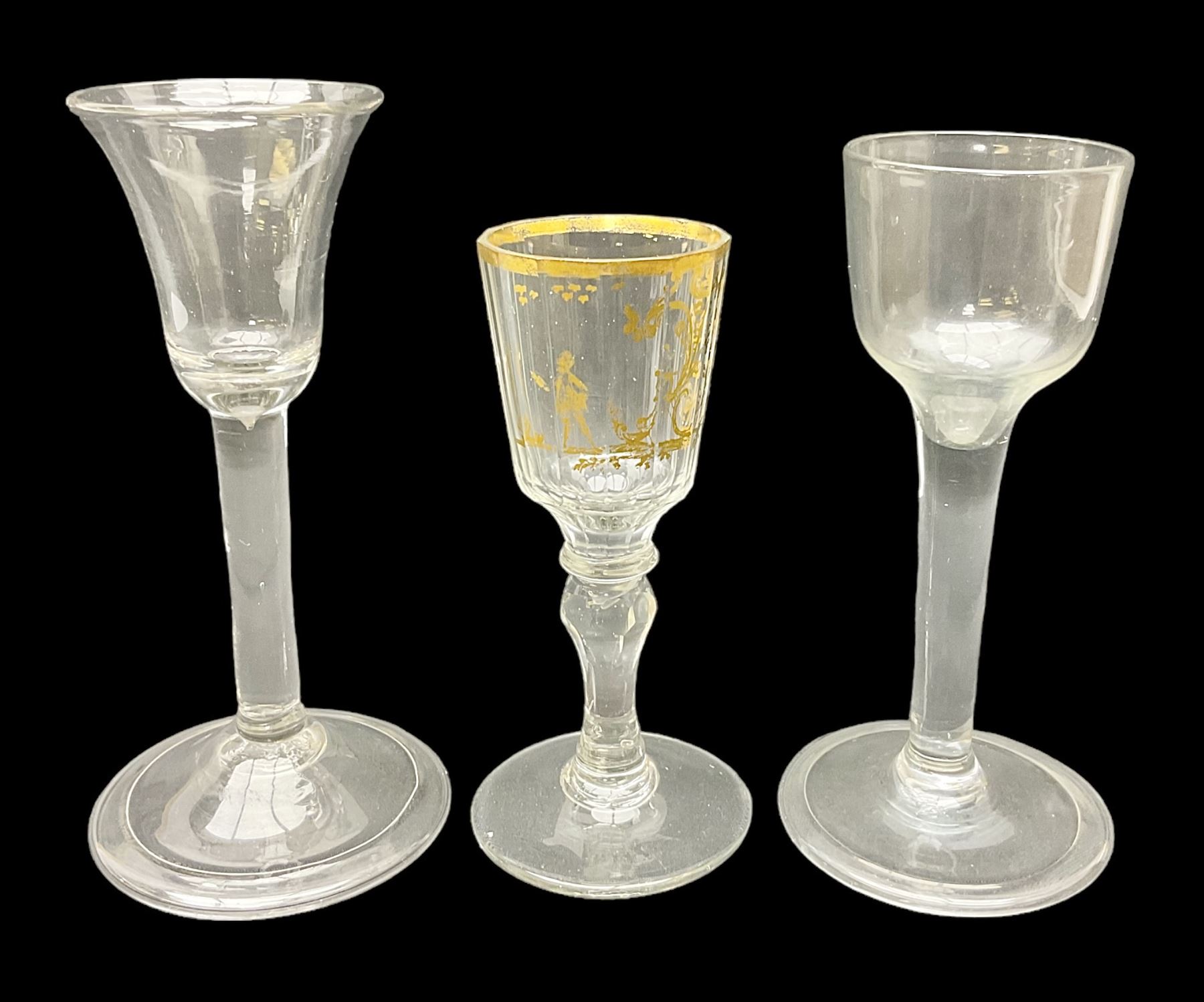 Three 18th century wine glasses comprising a plain stemmed glass with bell shaped bowl and conical folded foot H16cm, another plain stemmed glass with ogee bowl and folded foot and a Continental glass with gilt faceted bowl, decorated with male figure within a landscape, on a clear Silesian seven sided cut stem (3)