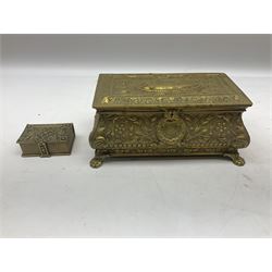 Collection of victorian and later brass desk accessories, to include a letter holder with cherub design, ink well of square form with hinged lid, brass table bell, brass casket with relief decoration, etc  