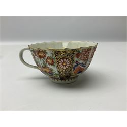 18th century Worcester teacup and saucer, circa 1770, of faceted form decorated in the Japanese Kakiemon style, similar to the Rich Queens pattern, with alternating panels of white formal chrysanthemums against a blue ground heightened with gilt, and flowering chrysanthemum plants and wheat sheaves, each with underglaze crescent mark beneath, teacup H4.5cm D8.5cm saucer D13.5cm