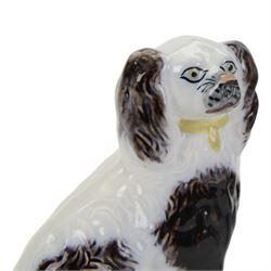 Pair of 19th century slip moulded pottery spaniels, circa 1840-1850, possibly Scottish, modelled with free standing forelegs and moulded fur with dark brown detailing and yellow glazed collars and padlocks upon a white ground, H17.5cm