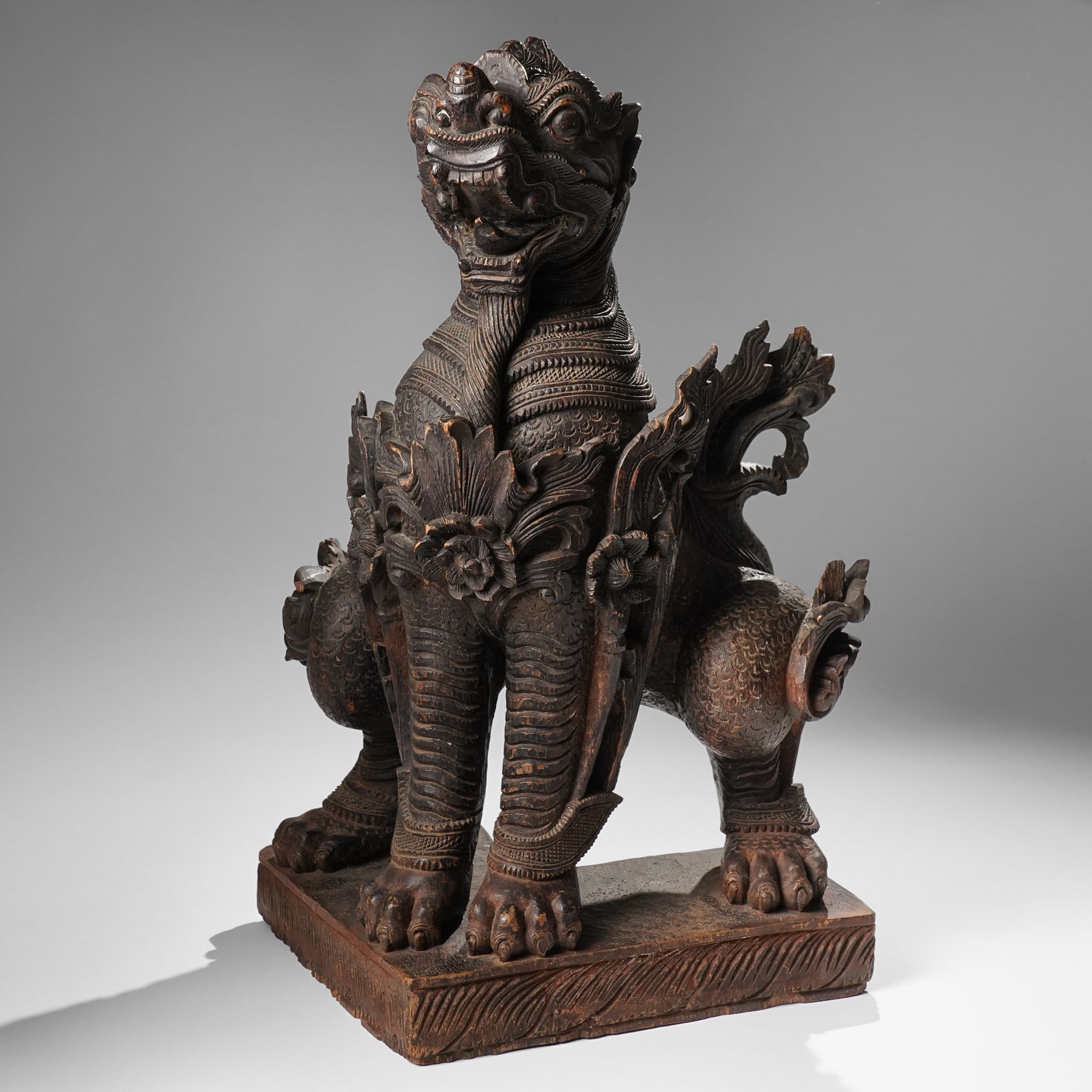 Burmese carved temple guardian figure, depicted seated with carved flame details, H52cm 