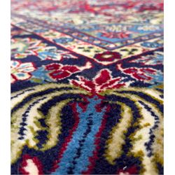 Central Persian Isfahan Carpet, hand-knotted, featuring a bold central rosette medallion on a rich red field, flanked by stylised floral sprays, scrolling foliage and mythical animals, within a broad indigo border decorated with alternating cartouches and flowerheads