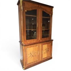 French style marquetry display bookcase, with twin glazed upper doors enclosing shelves, over a cupboard base inlaid with musical instruments and foliate decoration, the interior fitted with mirrored cupboard doors and a pull-out shelf, with gilt metal mounts and banding