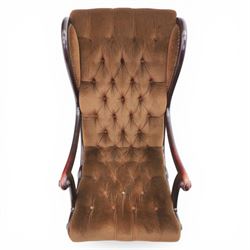 Late 20th century Regency style mahogany framed reading chair, the shaped and moulded frame with scrolled arms and open sides, upholstered in buttoned brown velvet, raised on curved supports terminating in scroll feet