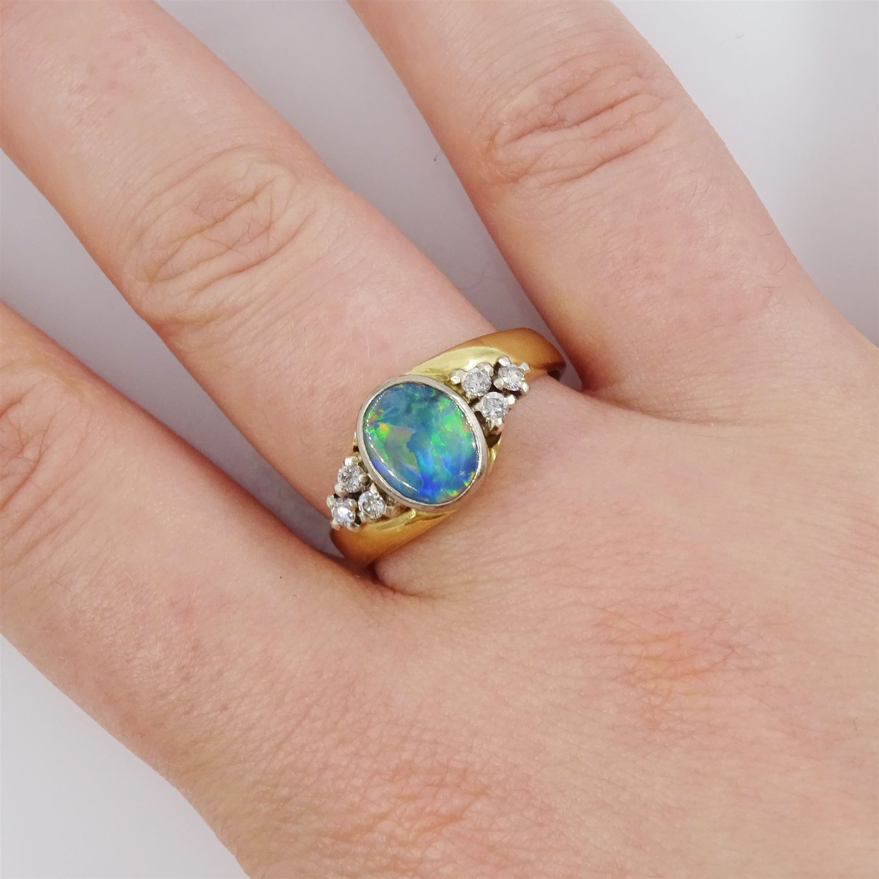 18ct gold opal and diamond ring, single oval cut opal, with three round brilliant cut diamonds set either side, stamped 750, total diamond weight approx 0.20 carat