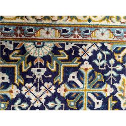 Persian indigo and pale gold ground rug, overall busy geometric design, the field decorated with hooked Hac and palmette medallions surrounded by densely patterned zig-zags and stylised foliate motifs, the border decorated with smaller Hac motifs, within multiple guard stripes 