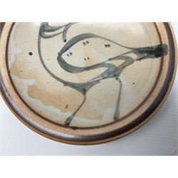 Studio pottery bowl, probably by Svend Bayer of Wenford Bridge, the stoneware body of shallow circular footed form with brushwork decoration of a stylised bird figure in grey upon peach ground within bands of iron red, unmarked, D18.5cm