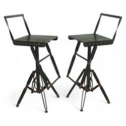Pair of 20th century brutalist industrial metal swivel bar stools, sheet seats with strap backrests with bolted design to the sides, raised on quadripod bases with angular strut supports, the seats height-adjustable and swivelling